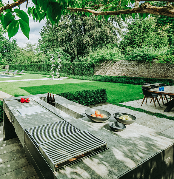 Gartenküche aus Naturstein auf Terrasse mit Blick in den großzügigen modernen Garten