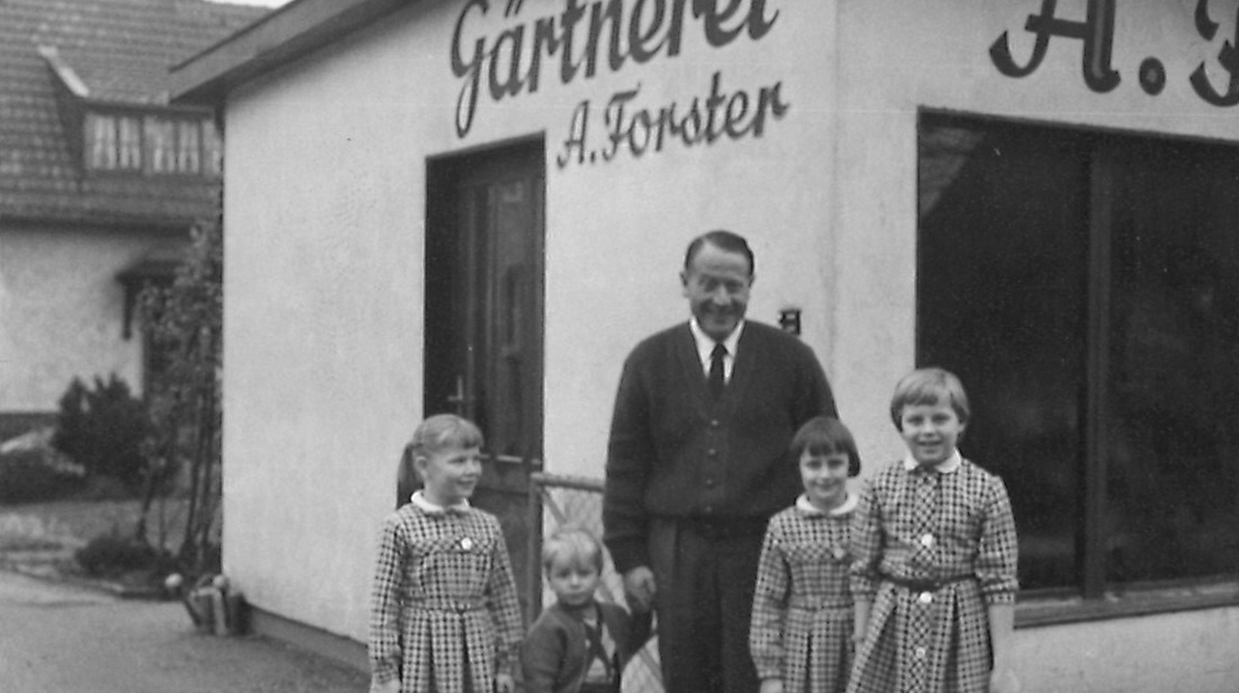 Ein schwarz/weiß Bild der Forster-Familie vor der damaligen Filiale. 
