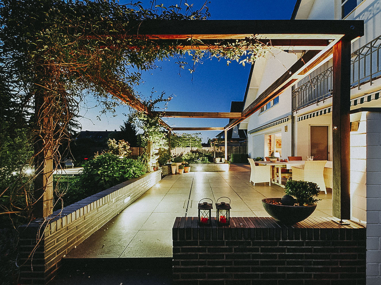 Terrasse aus großen Steinplatten mit Pergola und Gartenbeleuchtung