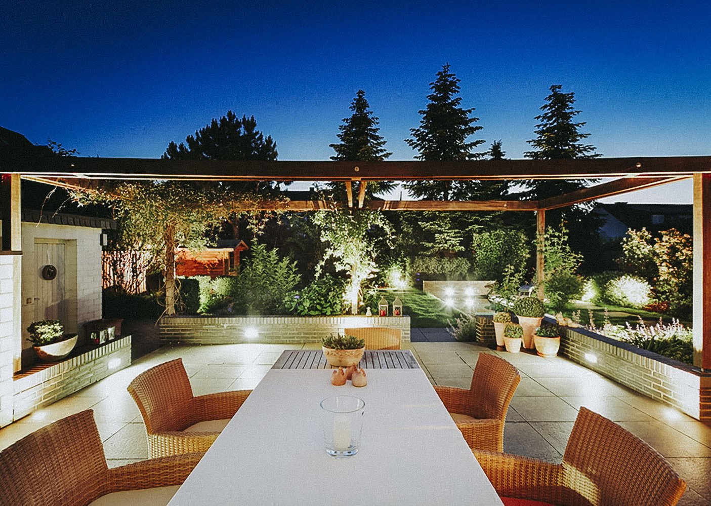 Terrasse mit Steinplatten und Sitzgruppe. Gartenbeleuchtung und Pergola