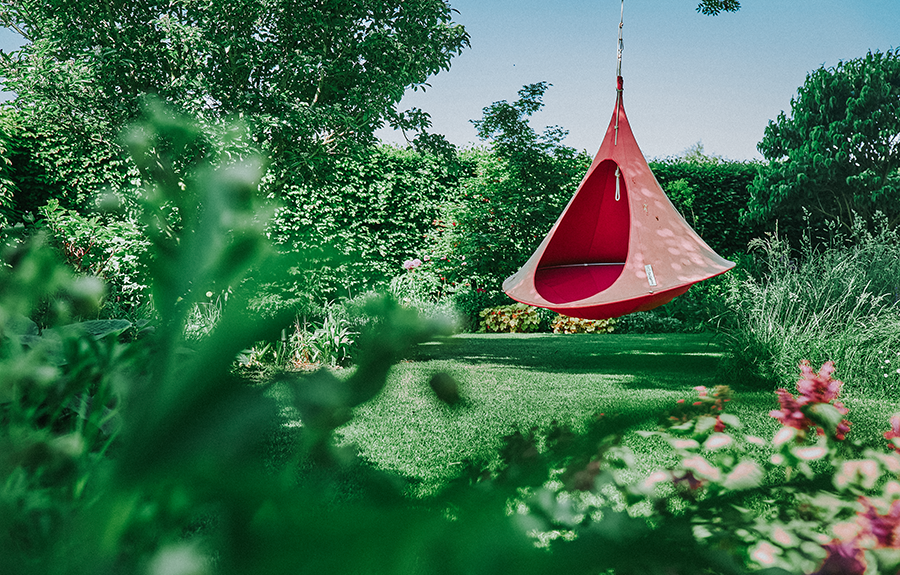 eine rote Zeltschaukel, die in einem Familiengarten am Baum hängt