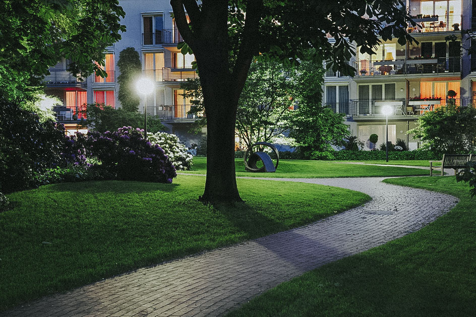 Gewerbegarten mit Rasenfläche, Staudenbeete, Gehölze und Kunst Objekt mit Beleuchtung am Abend